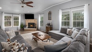 Una sala de estar con chimenea, sofá y ventilador de techo.