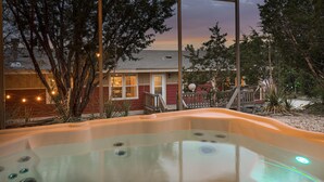 Un jacuzzi con vistas a una casa y árboles.