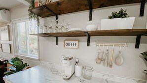 Eine Küche mit Marmorarbeitsplatten, einer Kaffeemaschine und Küchenutensilien, die an der Wand hängen.