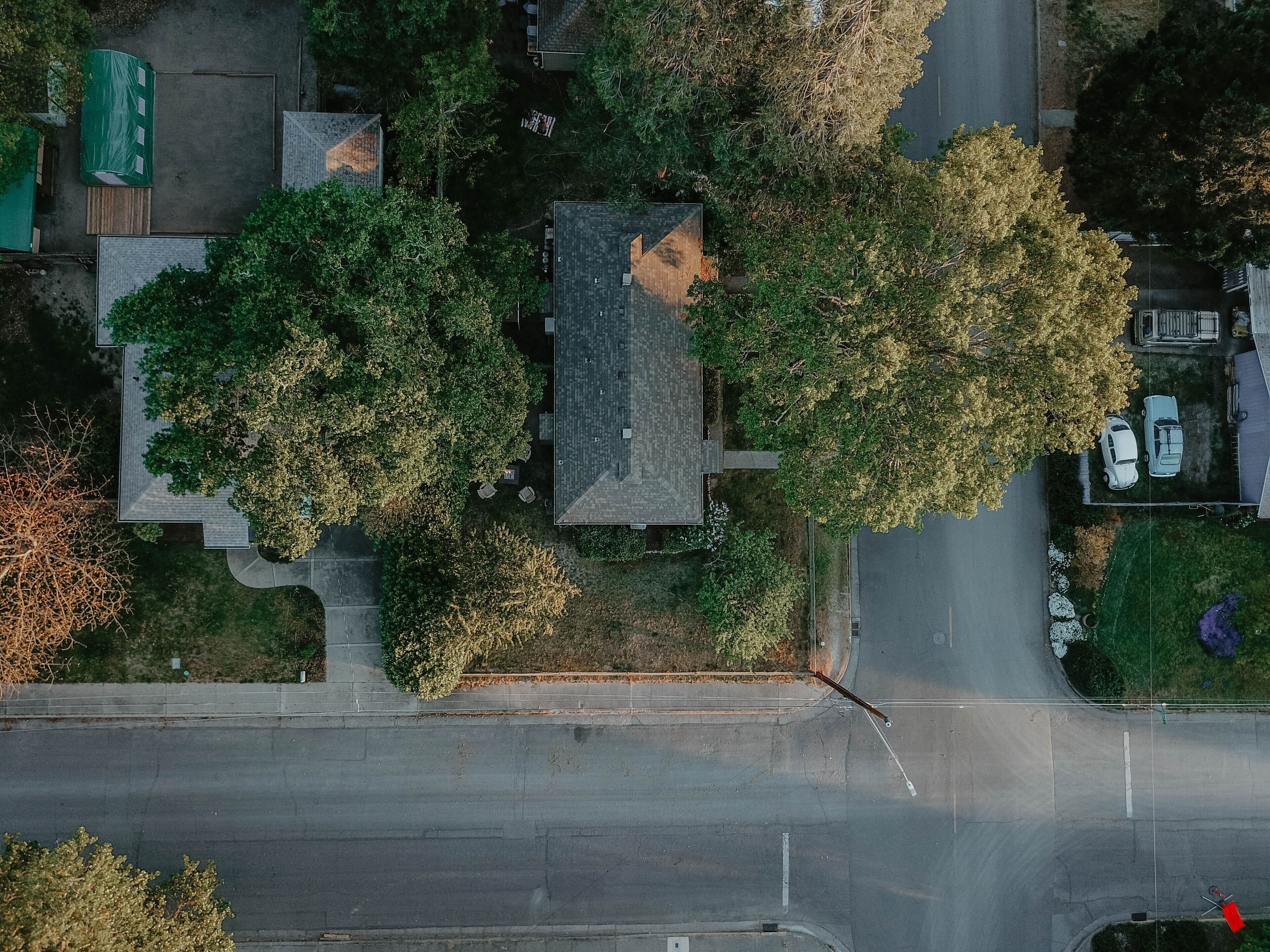 An aerial view of a residential area with houses, trees, and a road.