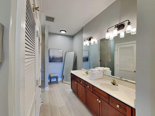 A modern bathroom with a large mirror, dual sinks, and a vanity with a towel stack.