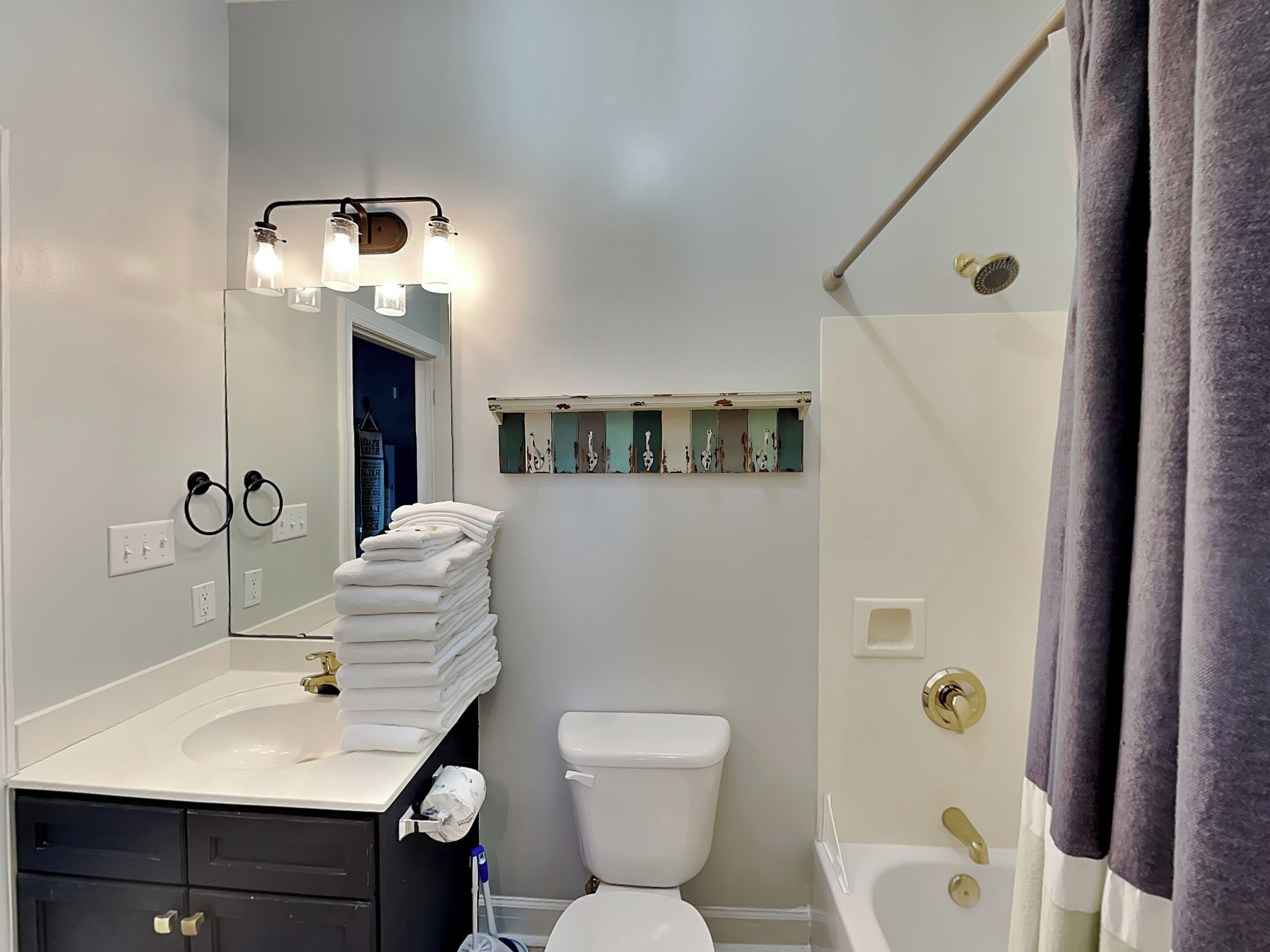 Une salle de bain équipée d’un lavabo, d’un miroir, d’un meuble-lavabo, de toilettes et d’une baignoire.
