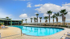 A pool area with lounge chairs and palm trees. - Tidewater #1003 | Gulf Front Orange Beach Condo! (Orange Beach)