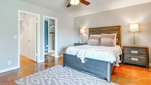 Un dormitorio con cama, mesitas de noche, ventilador de techo y alfombra estampada.