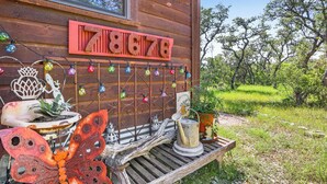 Una cabana de fusta rústica amb el número '7876' a la paret, envoltada de verdura.