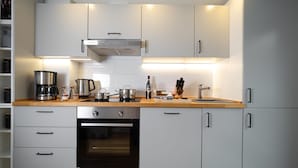 Une cuisine moderne avec des meubles blancs, un plan de travail en bois, un four encastré et divers appareils de cuisine.