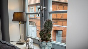 Un rebord de fenêtre orné d’un cactus dans un pot à motifs, une lampe et une petite figurine.