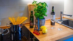 Un plan de travail de cuisine avec une casserole de spaghettis, une bouteille d’huile d’olive, un pot de basilic, une bouteille de vin et un citron.