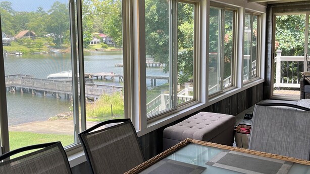 Ein Wintergarten mit Seeblick, einem Deckenventilator und einem Tisch mit Stühlen.