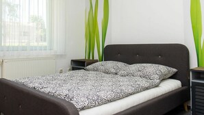 A bedroom with a bed, a window with sheer curtains, and tall green plants. - Wonderful private villa for 12 guests with private pool, A/C, WIFI, TV and terrace (Keszthely)