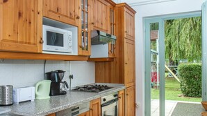 A kitchen with wooden cabinets, a microwave, a stove, and a sink. - Wonderful private villa for 12 guests with private pool, A/C, WIFI, TV and terrace (Keszthely)