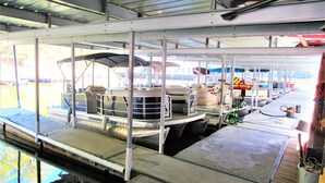 A boat with a covered seating area, a small wheelhouse, and a docked trailer. - Tiny Home at Kentucky Lake's Lynnhurst Family Resort (Murray)