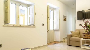 A modern living room with a beige sofa, a coffee table, and a flat-screen TV mounted on the wall. - La Casa Dei Ricordi Letojanni (Letojanni)