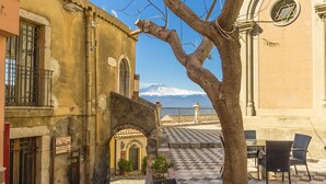 A courtyard with a checkered floor, outdoor seating, and a view of a snow-capped mountain. - La Casa Dei Ricordi Letojanni (Letojanni)
