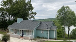 A single-story house with a porch, a garage, and a small deck. - Little Buck Bungalow - Deerfield Lake View Home on Norris Lake (LaFollette)
