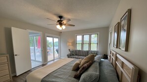 A bedroom with a bed, a ceiling fan, a window with blinds, and a door leading to a balcony. - Little Buck Bungalow - Deerfield Lake View Home on Norris Lake (LaFollette)