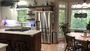 Una cocina moderna con una isla central, electrodomésticos de acero inoxidable y un comedor con vistas al exterior.