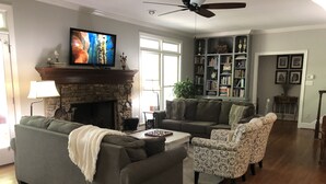 Una sala de estar con chimenea, televisión, estantería y comedor.