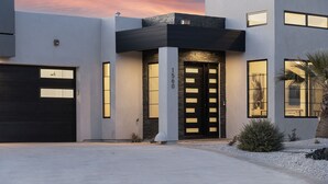 A modern two-story house with a black garage door, a central entrance with a black door, and a number "1560" on the wall.