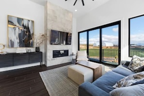 Un salon moderne avec une grande fenêtre, un canapé, une table basse et des œuvres d’art accrochées au mur.