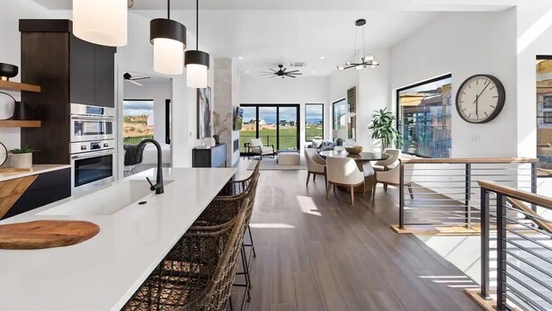 Una cocina moderna con una isla central, luces colgantes y vistas al exterior.