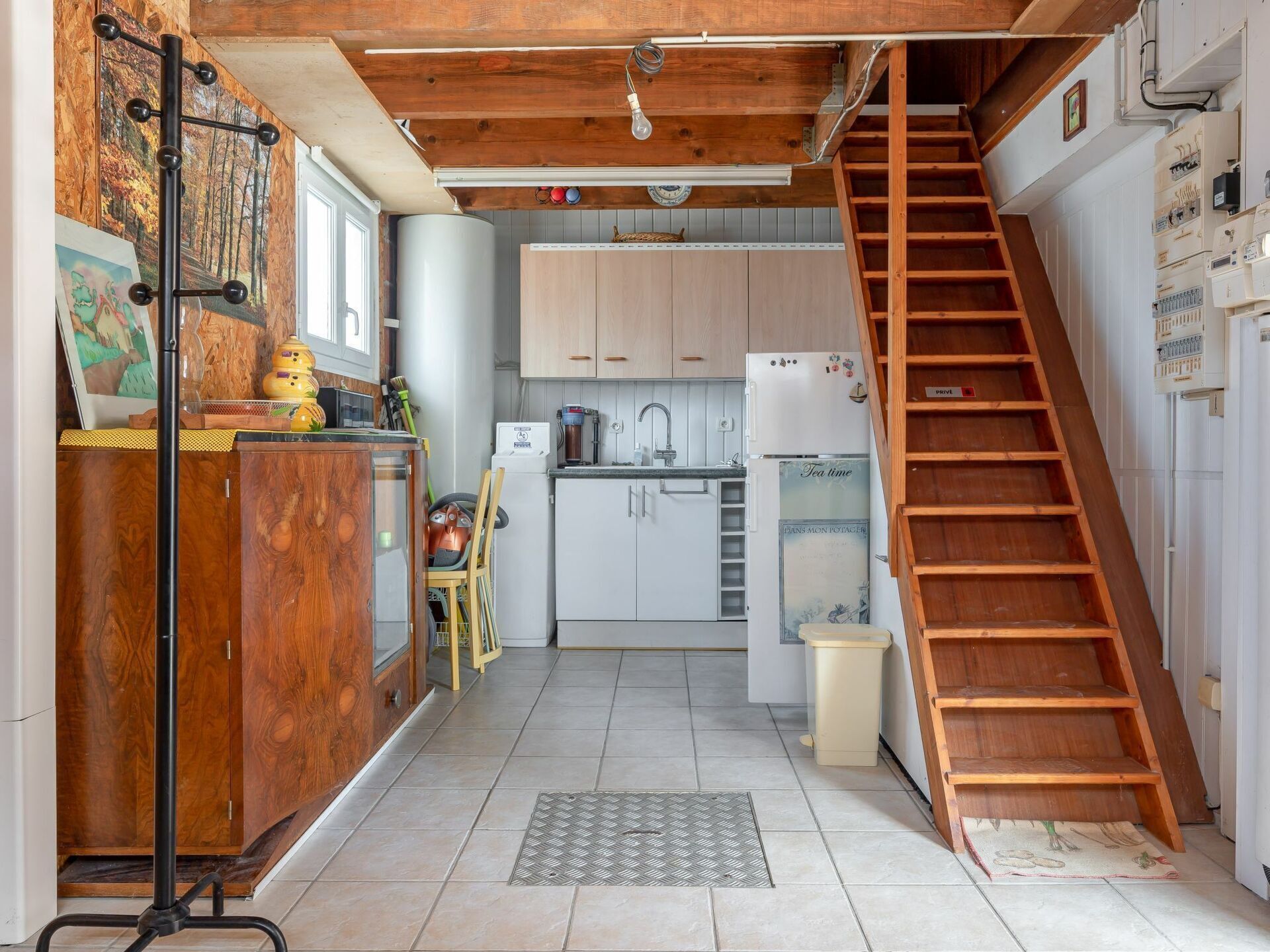 A compact kitchen with a wooden staircase, a dining area, and a small seating space.
