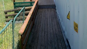 A wooden deck with a metal railing, a covered area, and a grassy field in the background. - Studio unit self contained, peaceful setting, awesome views  (Tokoroa)