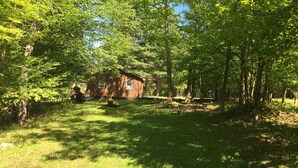 Ein rustikales Blockhaus, umgeben von dichtem Wald.