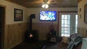Ein gemütliches Wohnzimmer mit Kamin, Fernseher und einer bequemen Couch.