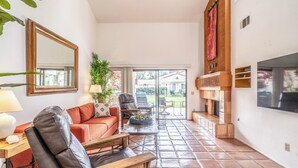 Un salón amplio con un sofá de cuero, una mesa de centro de madera y un televisor montado en la pared.