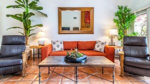 Una sala de estar con un sofá, dos sillones, una mesa de centro y un espejo grande en la pared.