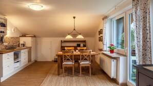 A modern kitchen with a dining table, chairs, and a hanging light fixture. - Apartment Brigitte in Garmisch-Partenkirchen with Mountain View (Garmisch-Partenkirchen)