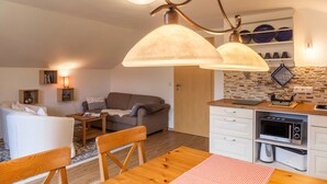 A compact living space with a kitchenette, a dining area, and a seating area with a sofa and a table. - Apartment Brigitte in Garmisch-Partenkirchen with Mountain View (Garmisch-Partenkirchen)