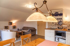 A compact living space with a kitchenette, a dining area, and a seating area with a sofa and a table. - Apartment Brigitte in Garmisch-Partenkirchen with Mountain View (Garmisch-Partenkirchen)