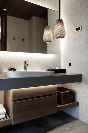A modern bathroom with a large mirror, a white sink, and two hanging light fixtures.