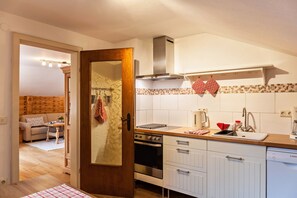 Une cuisine avec une porte en bois, des placards blancs, une cuisinière et un lave-vaisselle.