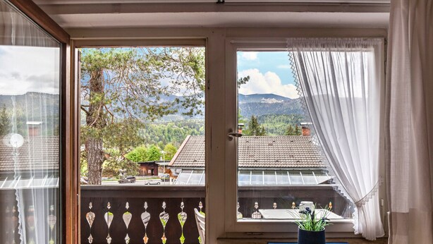 Habitació amb vista a un paisatge de muntanya, un balcó amb barana i una planta en test amb un davaluada.