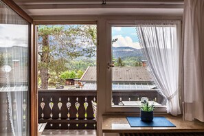 A room with a view of a mountain landscape, a balcony with a railing, and a potted plant on a windowsill. - Cosy Apartment Wank in Garmisch with Mountain View (Garmisch-Partenkirchen)