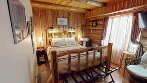 Une chambre située dans un chalet en rondins, avec un lit en bois, des lampes de chevet, une petite table et une chaise.