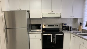 Una cocina moderna con electrodomésticos de acero inoxidable, incluyendo un refrigerador, microondas, horno y cafetera.