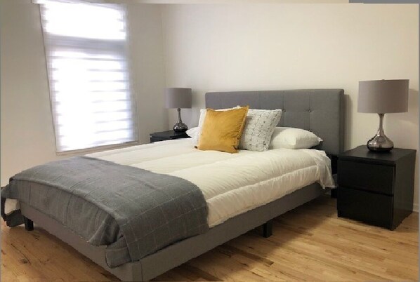 A bedroom with a bed, two bedside tables, a window with blinds, and a lamp on each table. - 2 bedroom gem in Little Italy, Montreal (MONTREAL)