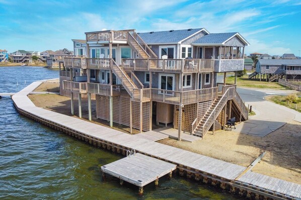 A multi-level waterfront house with a wooden deck and stairs leading to the upper levels. - Soundfront Home w/ Hot Tub, Private Launch Dock, Windsports Access. Winds Up! (Avon)