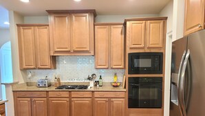 Una cocina moderna con gabinetes de madera, un refrigerador de acero inoxidable, un microondas y un horno.