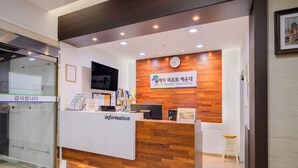 A reception desk with a clock, a sign for 'Pol-A Resort Haeundae', and a television above it. - Pol-A Resort Haeundae (Busan)