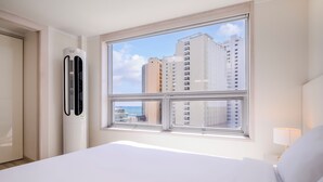 A hotel room with a bed, a window with a view of tall buildings, and a wall-mounted air conditioning unit. - Pol-A Resort Haeundae (Busan)