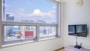 A room with a large window, a flat-screen TV mounted on the wall, and a small wooden cabinet. - Pol-A Resort Haeundae (Busan)