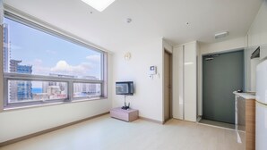 A modern apartment with a large window, a flat-screen TV, and a door leading to a balcony. - Pol-A Resort Haeundae (Busan)
