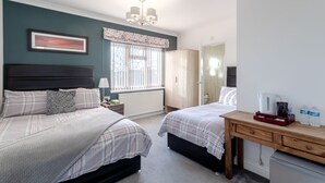 A bedroom with two beds, a desk, a radiator, a window with blinds, a mirror, and a chandelier. - Family room with private bathroom (Edgware)
