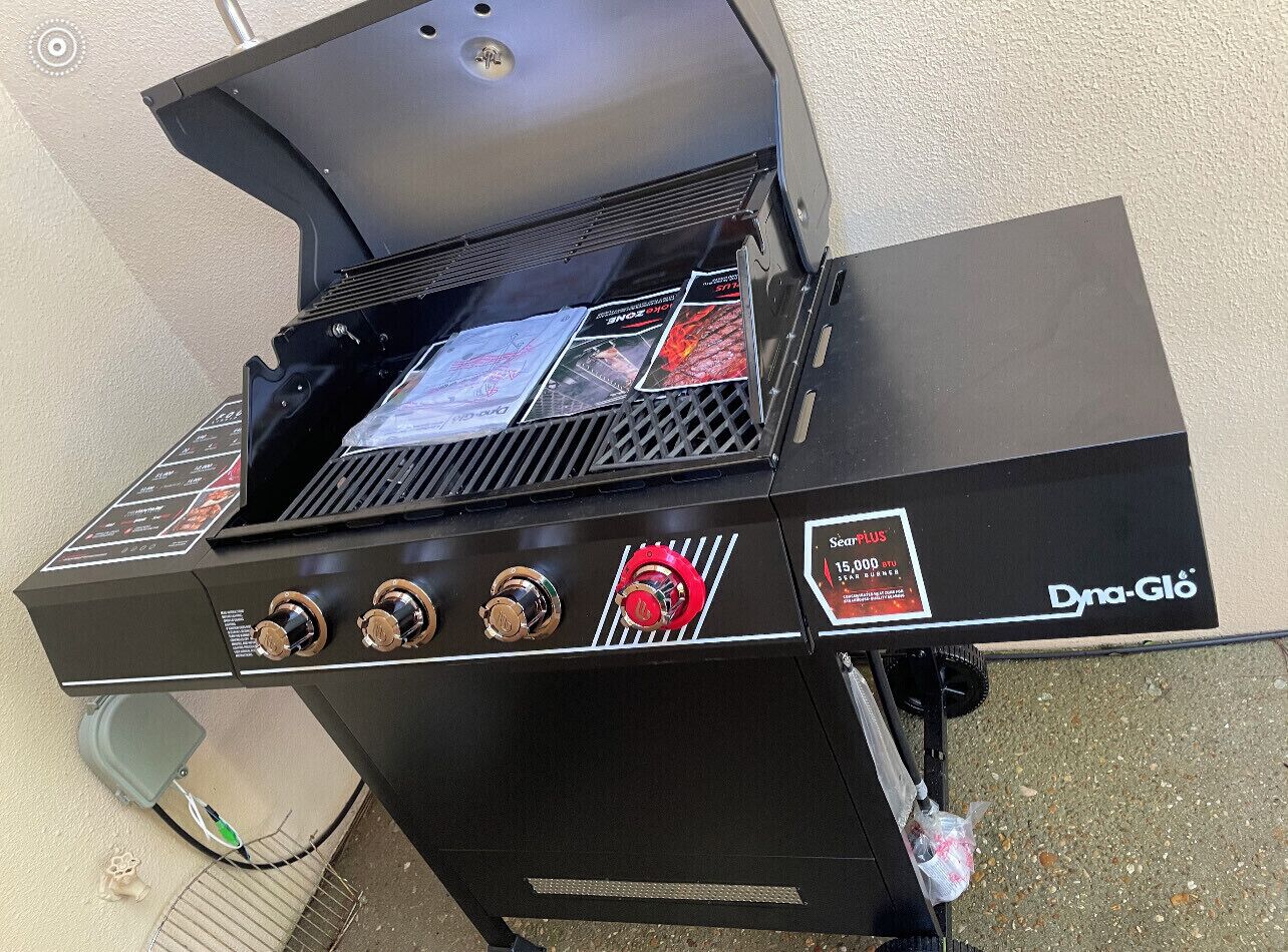 A black outdoor grill with four burners, a control panel, and a branded label.