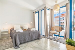Une chambre Ă coucher moderne avec un lit, une table de chevet, une lampe, une chaise et de grandes fenĂȘtres.